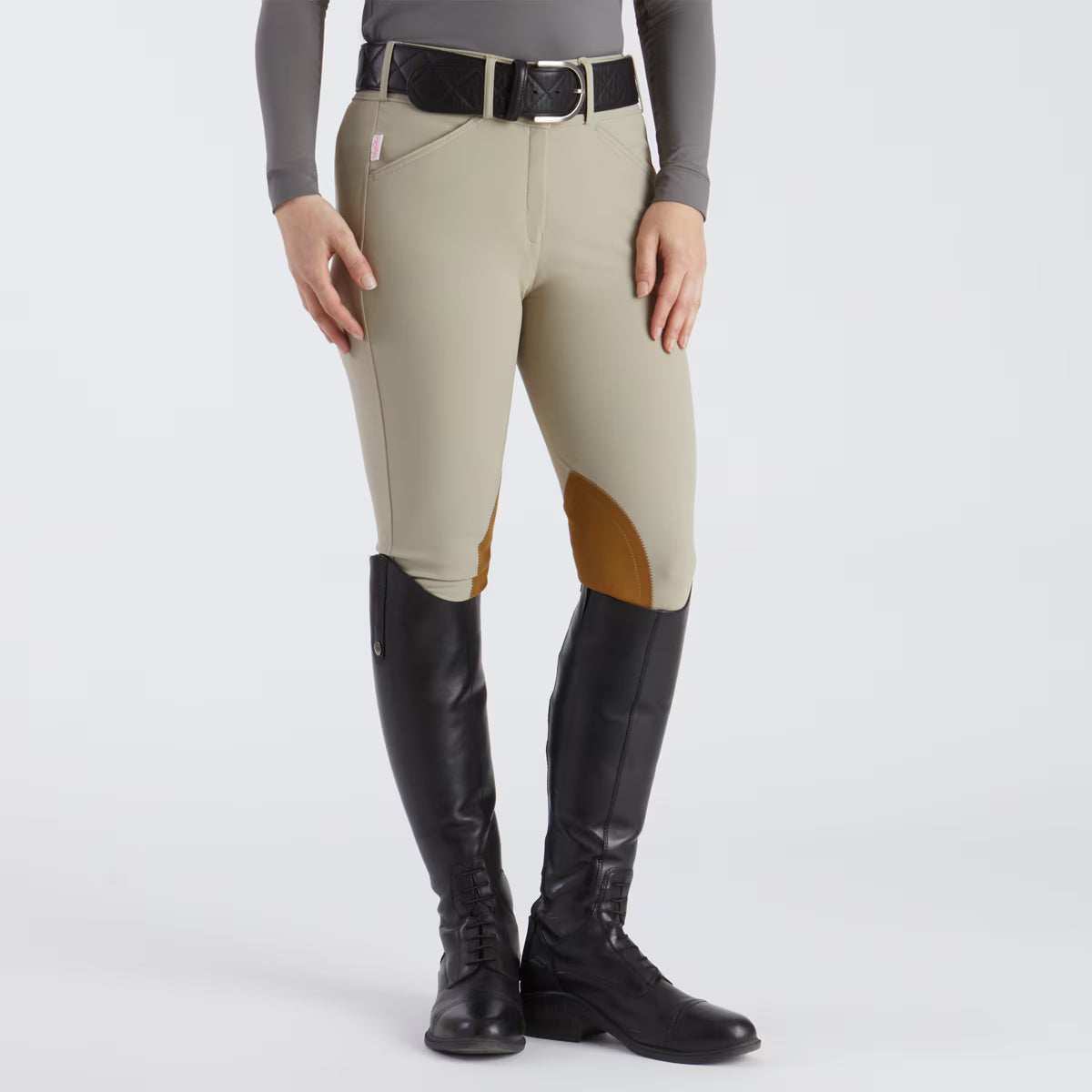 Person wearing beige riding pants with brown knee patches and black hunter jumper tall boots 